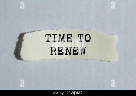 Time to renew message written on ripped torn paper piece on gray background. Conceptual time to renew symbol. Copy space. Stock Photo