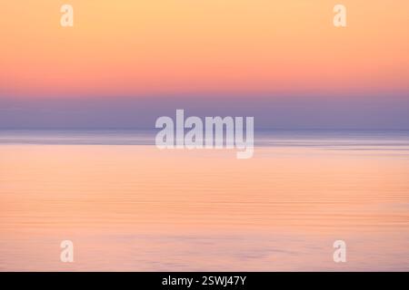 Vibrant hues blend seamlessly as the sun sets over calm waters, creating an ethereal atmosphere of peace and beauty, Intentional Camera Movement tecni Stock Photo