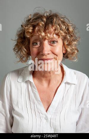 Mature Expressions: Forced Smile. From a series of expressive portrait images of a mature female model, studio shoot. Stock Photo