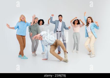 Diverse group of business professionals enjoying a collaborative team moment on a grey background in a joyful and dynamic atmosphere Stock Photo