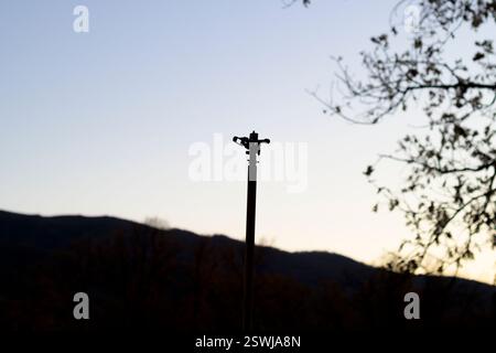 overhead water sprinkler standing backlit with clear sky and drought tree Stock Photo