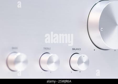 Detailed view of an audio amplifier's control knobs for bass, treble, and sound balance. The metallic surface complements the precision layout, reflec Stock Photo