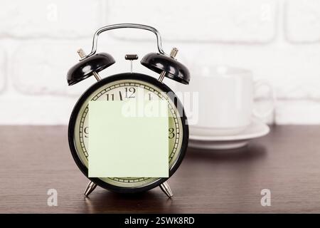 Reminder note and black old-fashioned alarm clock Stock Photo