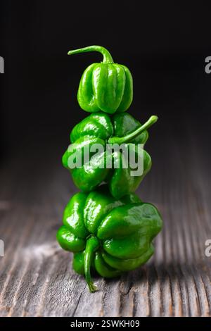 Three ripened green habanero peppers (capsicum chinense) on wooden table. Very hot mexican peppers on rustic wooden table close up Stock Photo