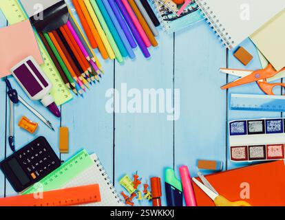 Bright and colorful workspace filled with various school and craft supplies arranged on a blue wooden table Stock Photo