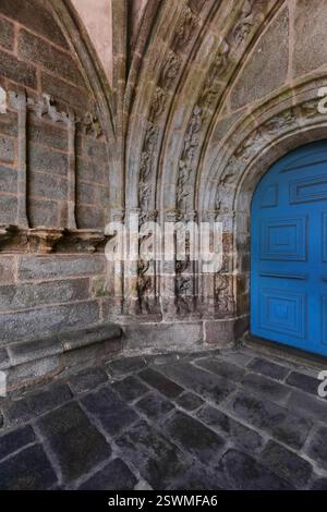 315 The Grand Porch of the Saint Ronan Church hosts a double door with wood leafs painted blue framed by sculpted archivolts. Locronan-Brittany-France Stock Photo