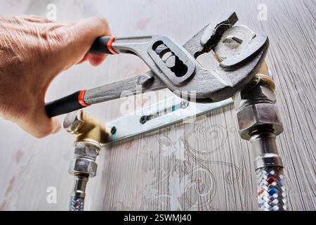 Plumber is installing pipe plug using adjustable pliers. Stock Photo