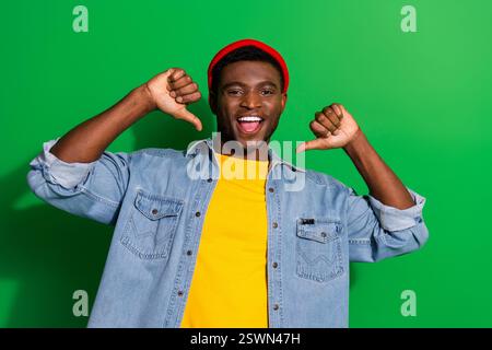 Enthusiastic young male model in casual denim shirt looking confident and trendy with a cheerful smile and a green background. Stock Photo
