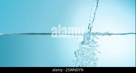 Front view of water jet filling a water tank with bubbles against blue background Stock Photo