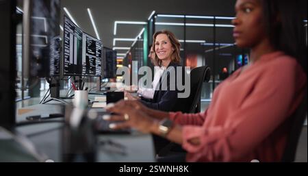 African American coder happily coding on desktop in diverse office. Stock Photo