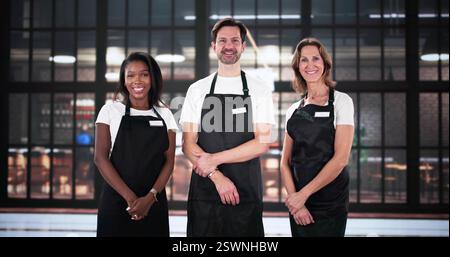 Smiling server and manager pose for restaurant portrait in uniform. Stock Photo