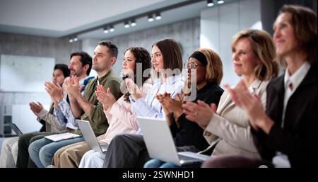 Thrilled crowd at business event watching diverse speakers presenting. Applauding. Stock Photo