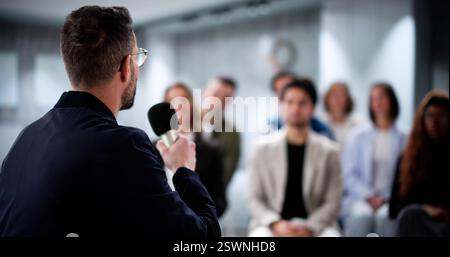 Business Speaker Engages Diverse Audience in Educational Financial Presentation. Stock Photo