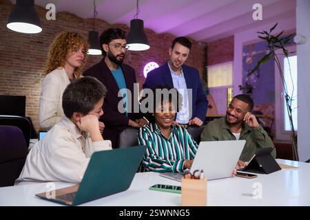 Diverse business team collaborating on project using laptop in modern office Stock Photo