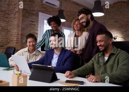 Marketing team analyzing data on laptop and tablet in office meeting Stock Photo