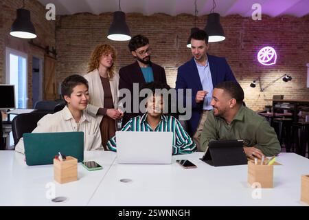Diverse business team collaborating on project using laptop in modern office Stock Photo