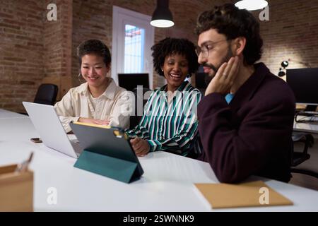 Business team analyzing data on tablet and laptop in office meeting Stock Photo
