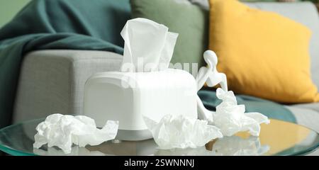 White box and crumpled tissues on glass table in room Stock Photo