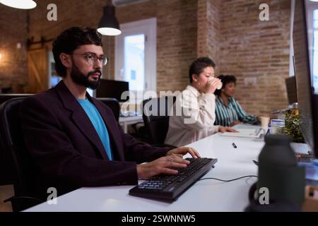 Focused employee typing on keyboard in busy office Stock Photo