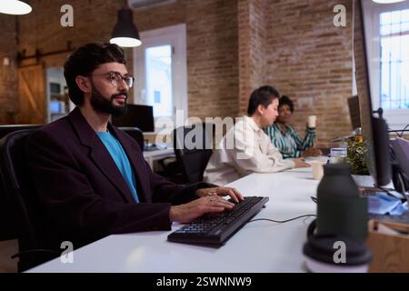 Focused employee typing on keyboard in busy office Stock Photo