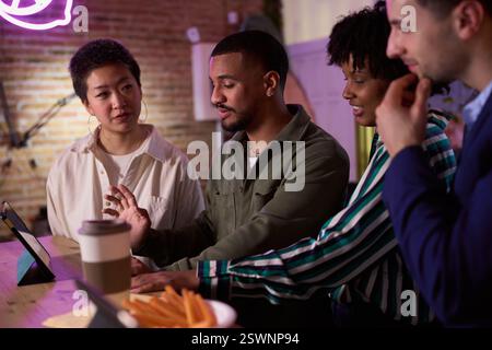 Diverse business team collaborating on a project using tablet in modern office space Stock Photo