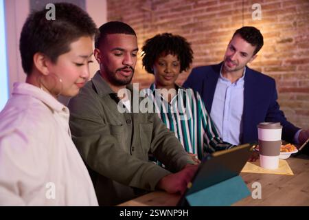 Creative team using tablet, discussing project in cafe Stock Photo