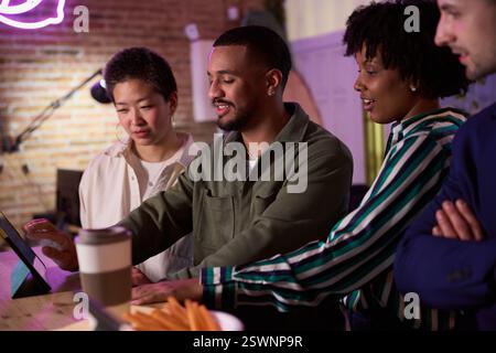 Diverse team collaborating on digital tablet in modern office Stock Photo