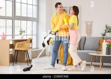 Young couple vacuum cleaning in room on spring day Stock Photo
