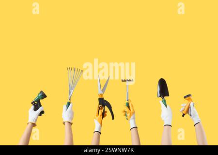 Female hands with gardening tools on yellow background Stock Photo