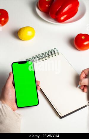 Planning healthy menu concept. Smartphone with green screen in hands. Calculating calories. Nutrients counting. Calorie tracking app mock up. Stock Photo