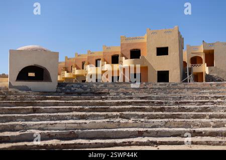 Crumbling concrete stairs lead to an abandoned, unfinished resort building in marsa alam, egypt, under a clear blue sky Stock Photo