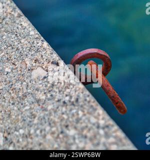 Rusty iron mooring ring for boat on concrete pier against sea water background. Montenegro Stock Photo