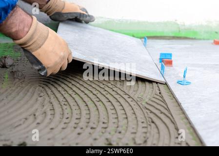 Bricklayer tiler places tiles for a new floor on cement glue. Construction industry. Building. Stock Photo