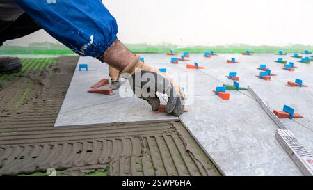 Bricklayer tiler installs tiles using leveling spacers. Construction industry. Building. Stock Photo