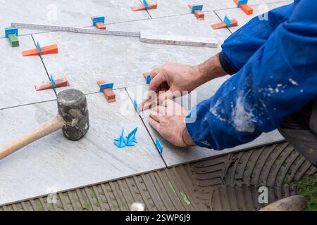 Bricklayer tiler installs tiles using leveling spacers. Construction industry. Building. Stock Photo