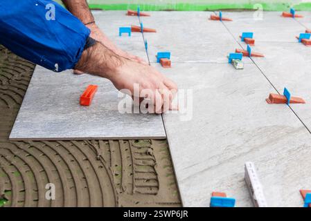 Bricklayer tiler installs tiles using leveling spacers. Construction industry. Building. Stock Photo