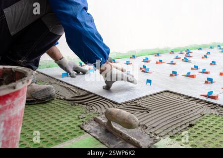 Bricklayer tiler installs tiles using leveling spacers. Construction industry. Building. Stock Photo