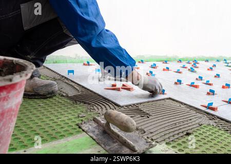 Bricklayer tiler installs tiles using leveling spacers. Construction industry. Building. Stock Photo