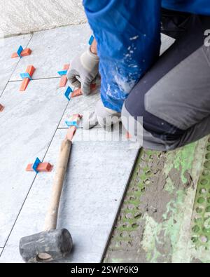 Bricklayer tiler installs tiles using leveling spacers. Construction industry. Building. Stock Photo