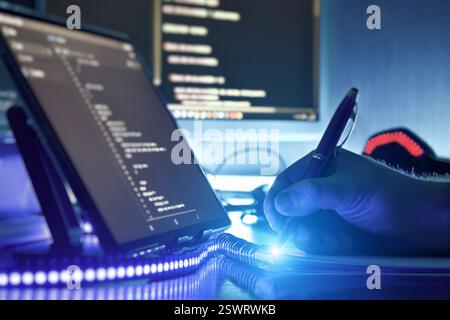 Modern programmer working on coding in futuristic workspace with blue ambient lighting and digital Stock Photo
