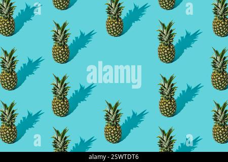Trendy sunlight summer fruit pattern made of pineapples on light blue background with copy space. Nature summer concept. Ananas backdrop idea image. Stock Photo