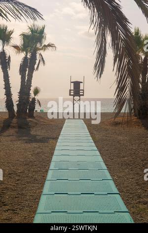 Low angled view along beach boardwalk towards the lifeguard tower and a view over the horizon beneath sunny blue skies Stock Photo