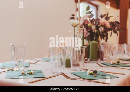 Beautiful table arrangement featuring glasses, green napkins, and floral centerpiece decorations. Stock Photo