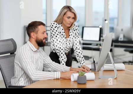 Technicians making digital engineering drawing on computer at desk in office Stock Photo
