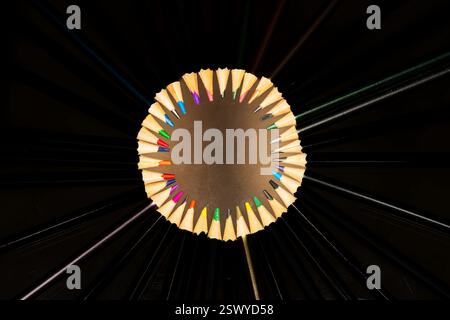 Radial Arrangement of Black Pencils with Exposed Colorful Tips Forming a Circular Composition Against a Dark Background Stock Photo