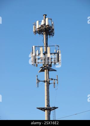 Modern cellular tower with numerous cells visible against a clear blue sky. Stock Photo