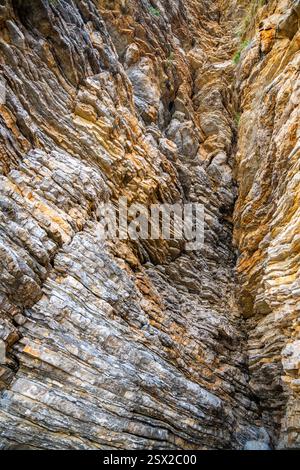 Layered rock texture in Budva, Montenegro. Sedimentary rocks with rugged surface of gray and ...