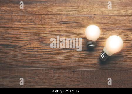 two glowing bulbs on a wooden table Stock Photo