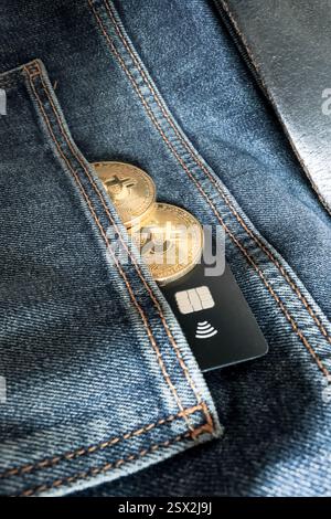 Credit card next to two Bitcoin physical coins inside a blue jeans pocket Stock Photo