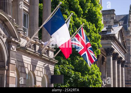 French flag and Union Jack flying side by side on flagpoles outside a historic building in Edinburgh, UK. Might depict European travel or allied natio Stock Photo